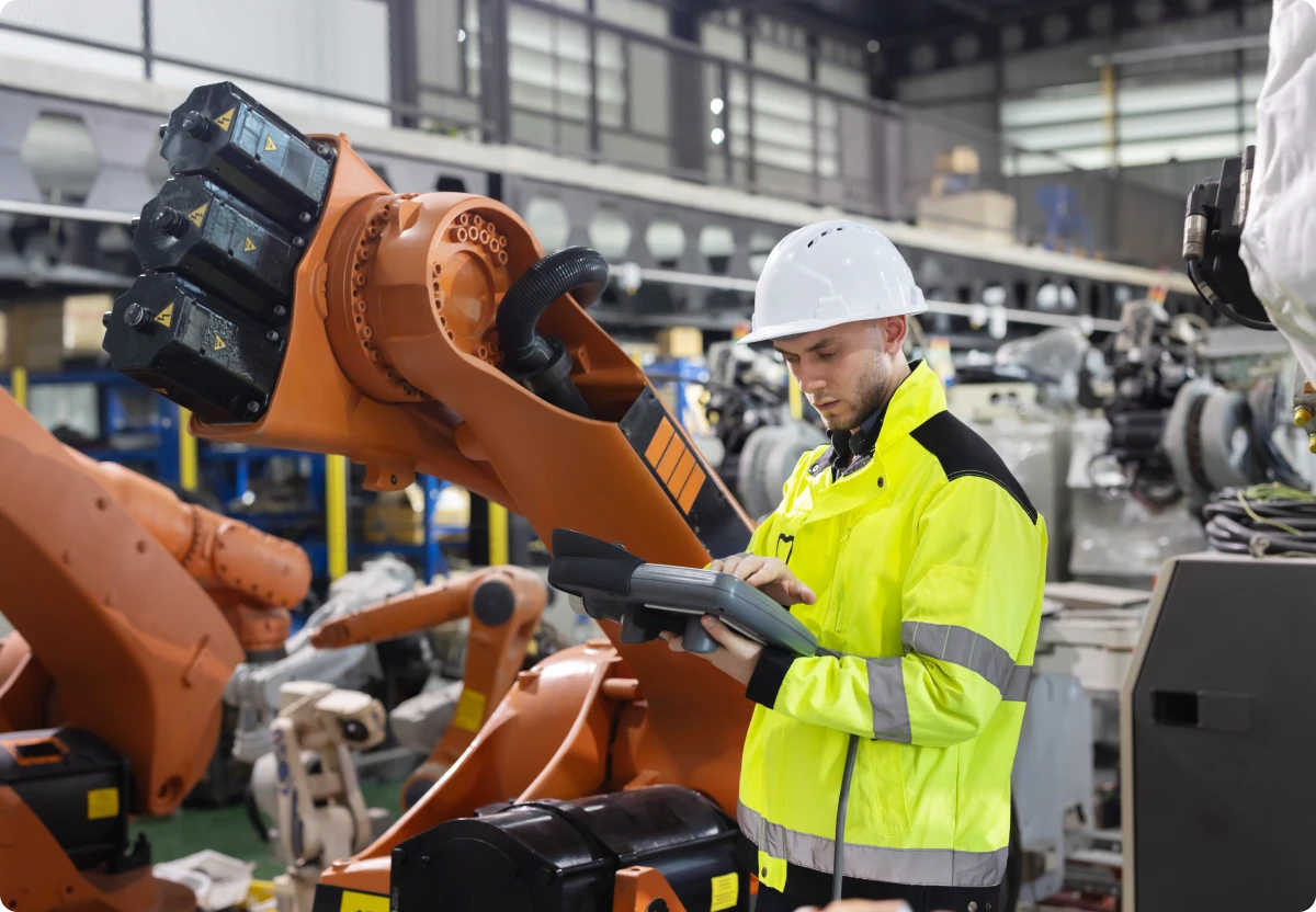 Engineer operating robotic arm in factory